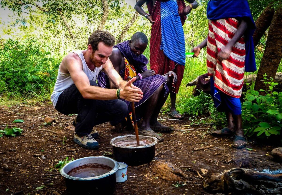 Maasai villagers in traditional red robes standing in front of their circular village huts in northern Tanzania