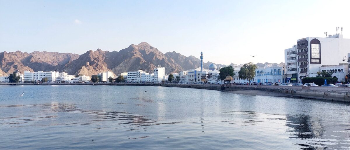 Night view of Muscat with illuminated buildings and mountains in the background, seen from above