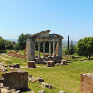 Panoramic view of an Albanian hillside town with stone-roofed houses and a historic fortress overlooking a valley under a soft off-season sky