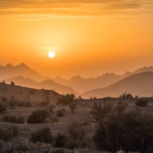 Panoramic view of Muscat with traditional white buildings, mosque domes and coastal mountains at sunset in Oman