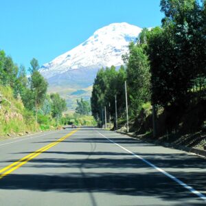Panoramic view over Ecuador’s snow-capped Andean volcanoes at sunset with winding road in the foreground