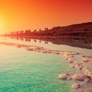 Panoramic view over Jordan’s desert landscape with sandstone mountains and golden sand dunes under a clear blue sky
