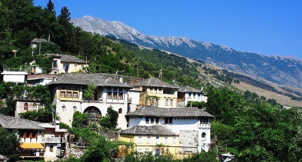 Panoramic view over the historic city of Berat in Albania, with white Ottoman houses and hundreds of windows cascading down a green hillside above the river