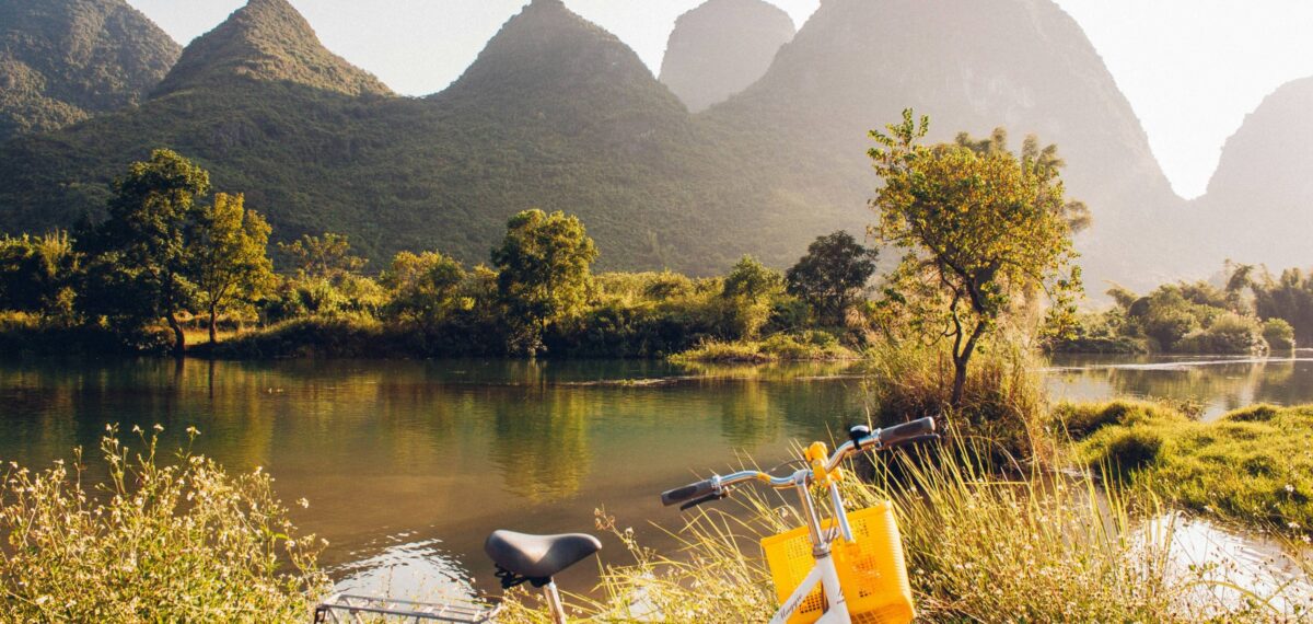 Parents and small children cycling along a narrow country road through rice fields and karst hills near Yangshuo