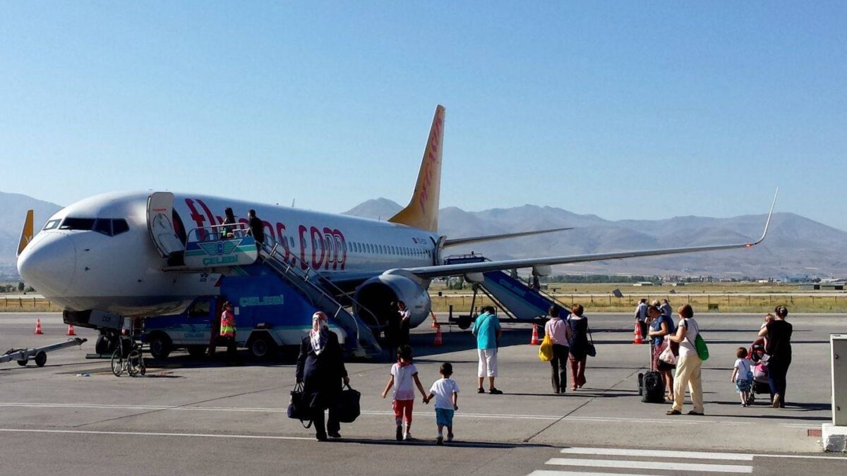 Passenger airplane taxiing on a runway with mountains in the background at sunrise