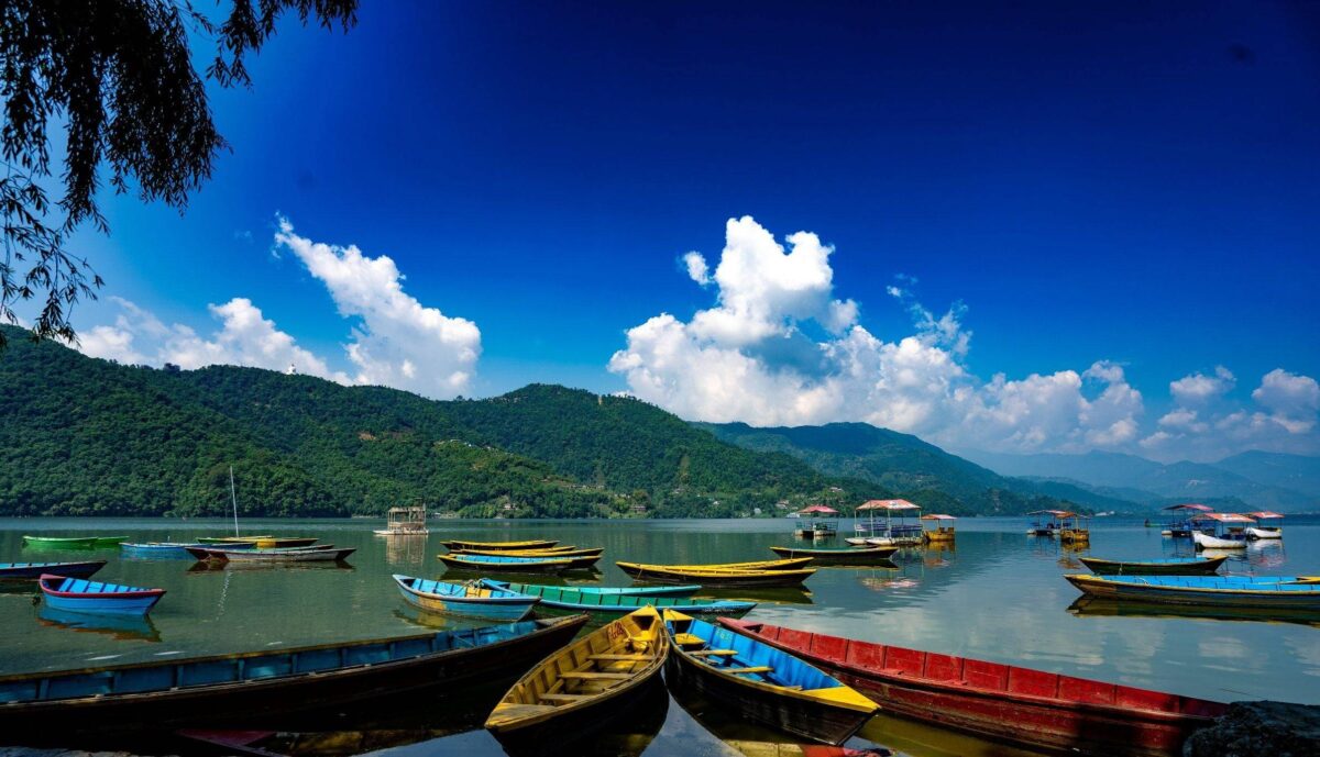 Peaceful lake in Pokhara with colorful boats and Annapurna range in the background