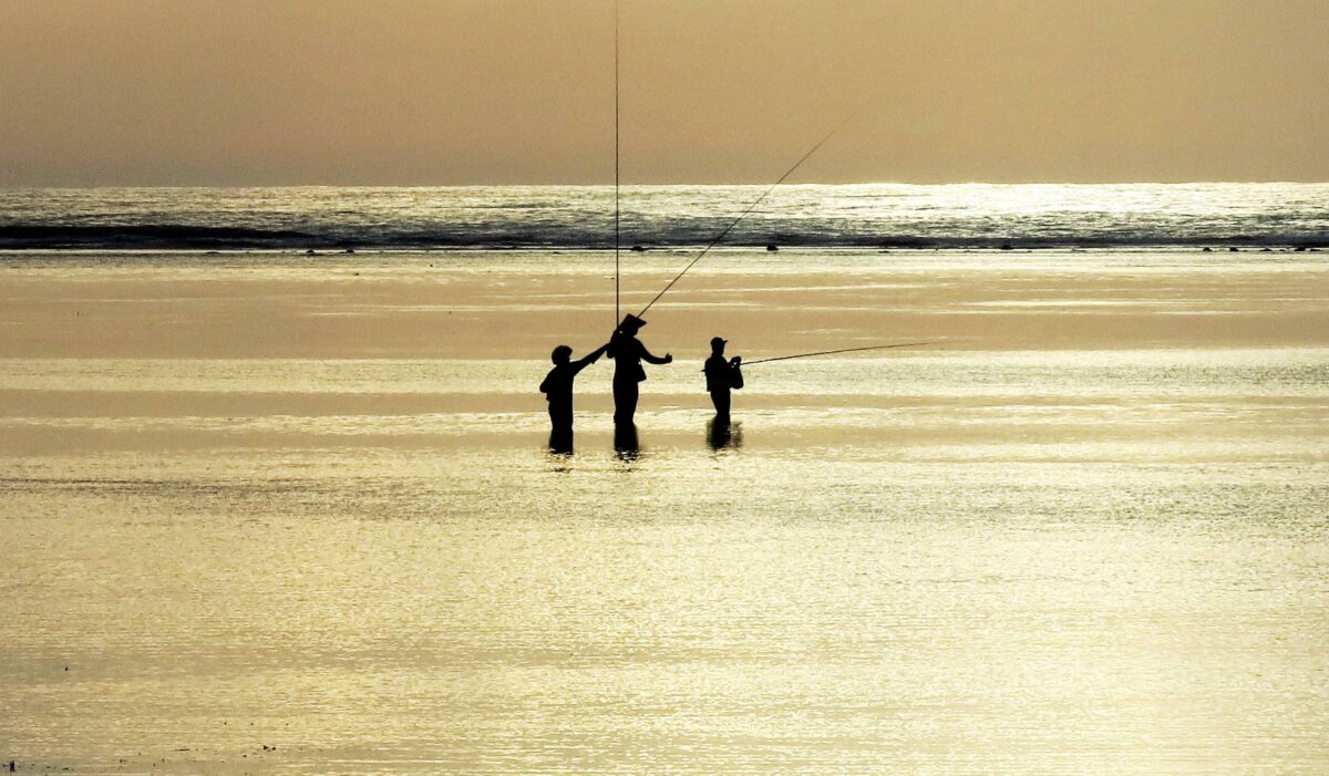 Peaceful sunrise or sunset on Sanur beach with calm sea, fishing boats and a sandy shoreline
