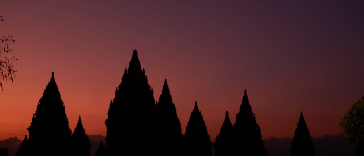 Prambanan Hindu temple complex near Yogyakarta at sunset with illuminated stone towers