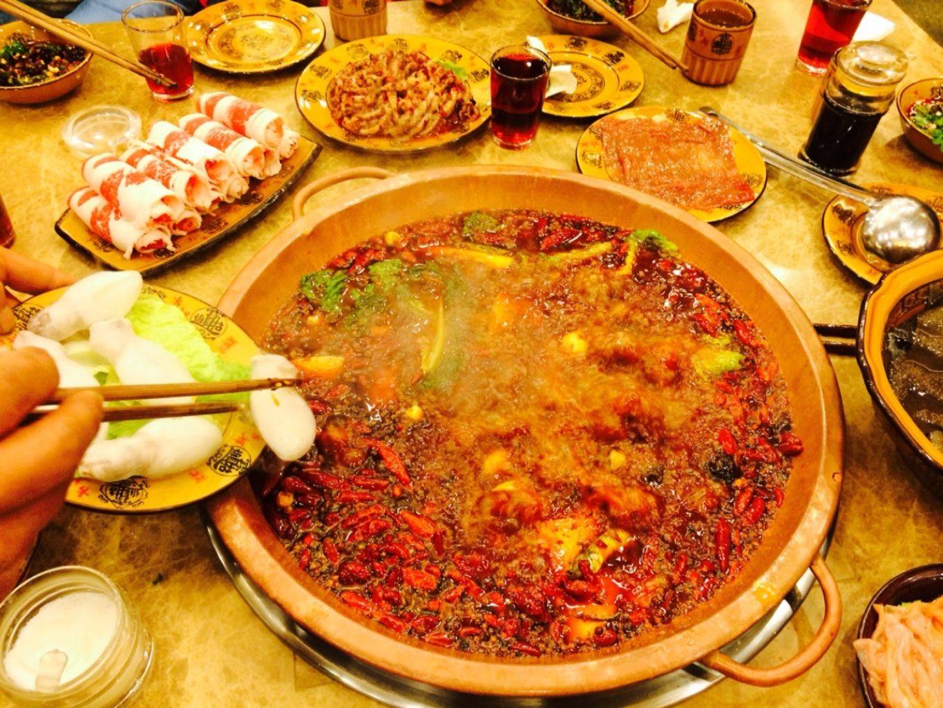 Traditional Sichuan hot pot bubbling with red chilies and peppercorns on a table in Chengdu
