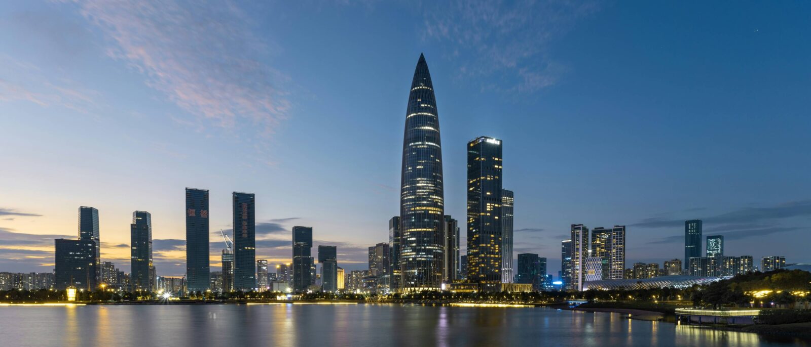 Family arriving in Shenzhen, looking up at the illuminated skyscrapers of the modern city
