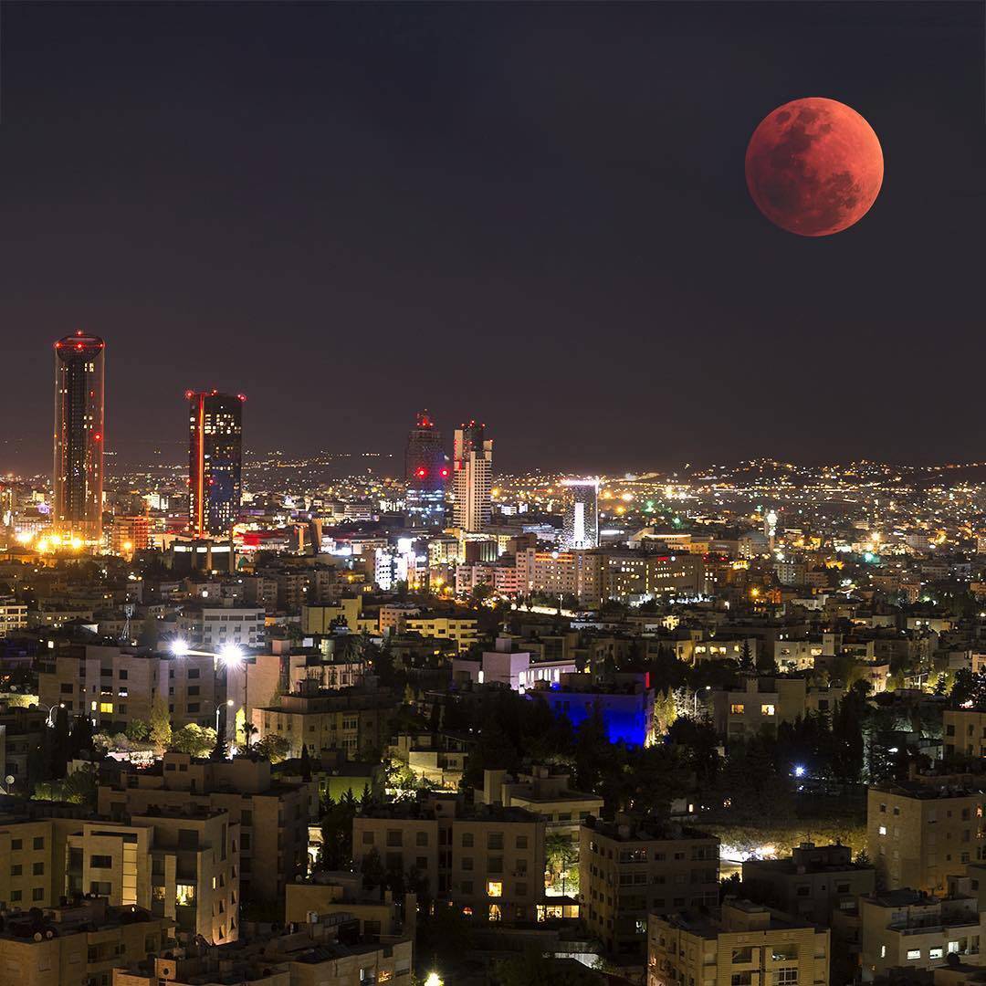 View of Amman city with houses stacked on hillsides under a clear sky