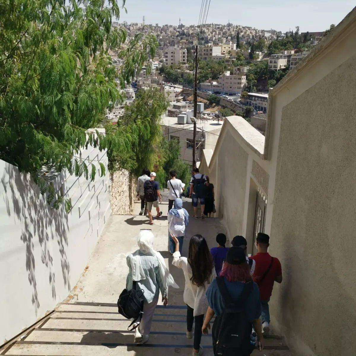 Family walking through Amman old town with view of the Citadel and Roman Theatre