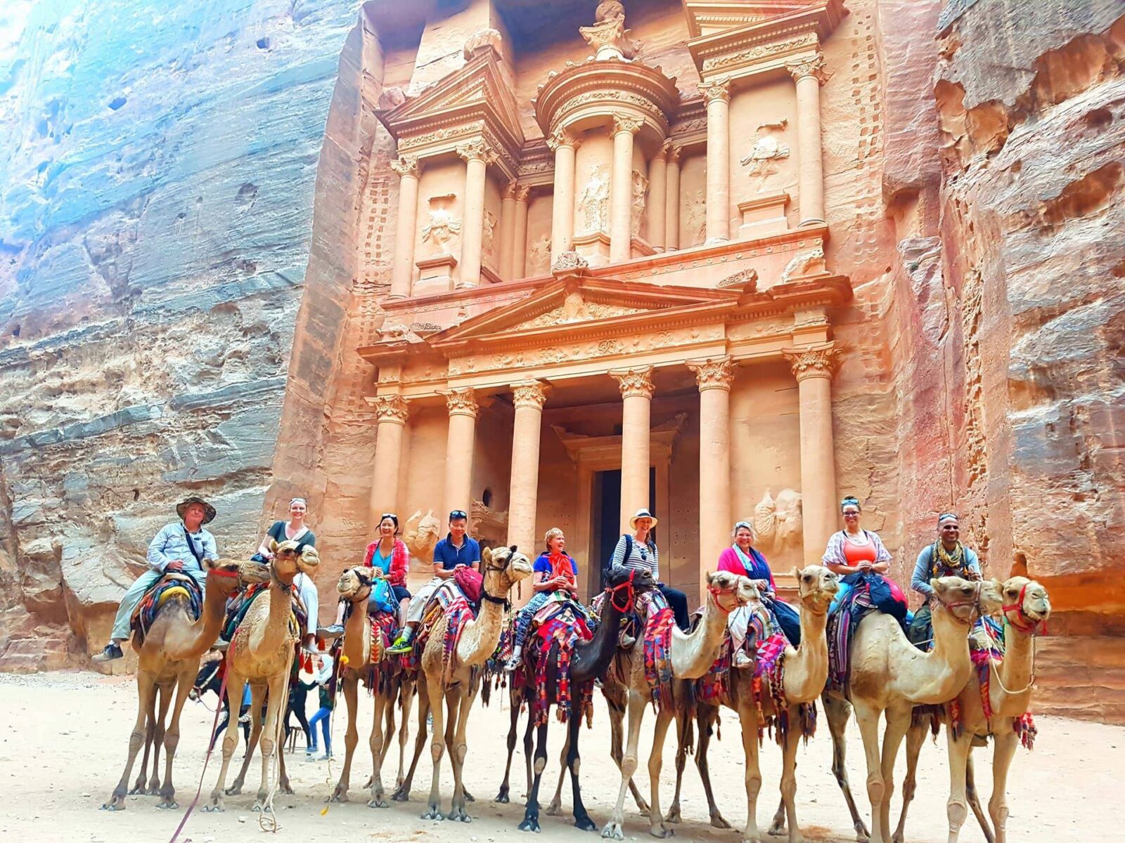 Family standing in front of the Treasury in Petra framed by the narrow Siq canyon