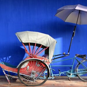 Family standing on a tropical Malaysian beach at sunset, with lush green hills and calm sea in the background