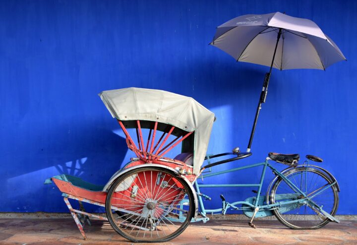 Family standing on a tropical Malaysian beach at sunset, with lush green hills and calm sea in the background