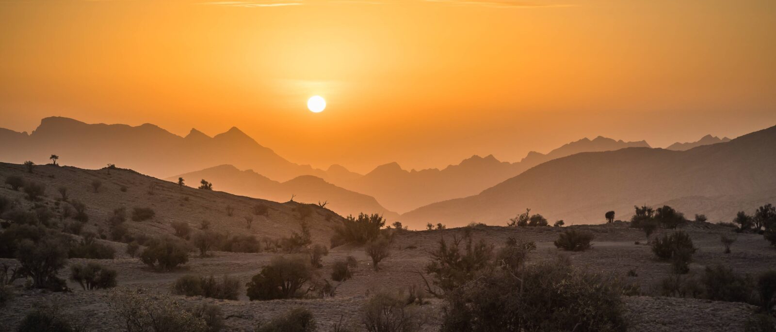 Dramatic canyon walls and rugged cliffs of Jabal Shams with a village of traditional mud houses below