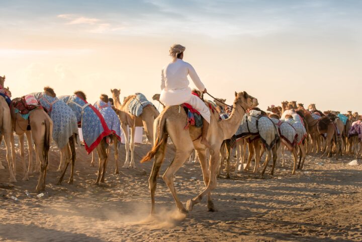 4x4 vehicle with roof-top tent parked in the Omani desert at sunset with high sand dunes in the background