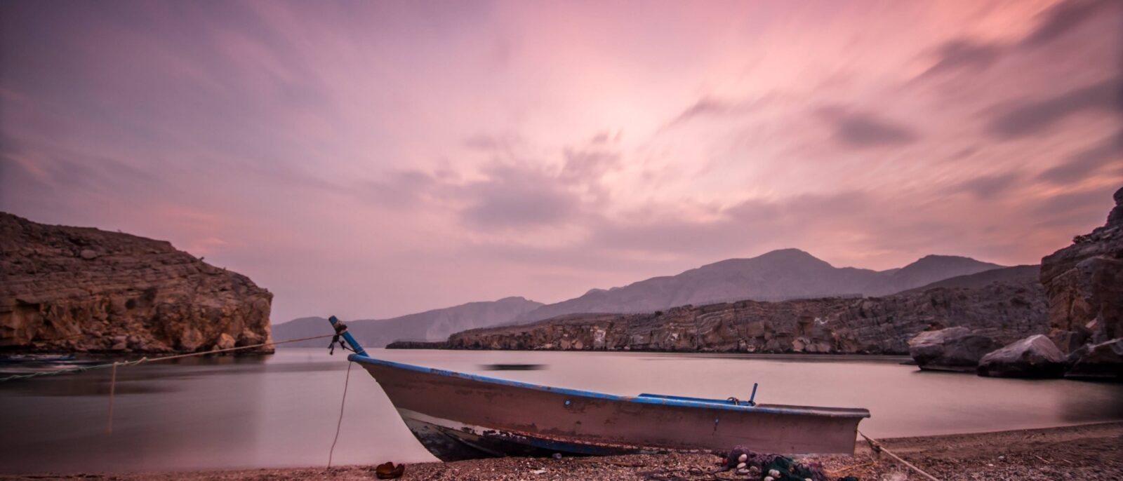 Passenger aircraft taking off from Muscat Airport with mountains in the background