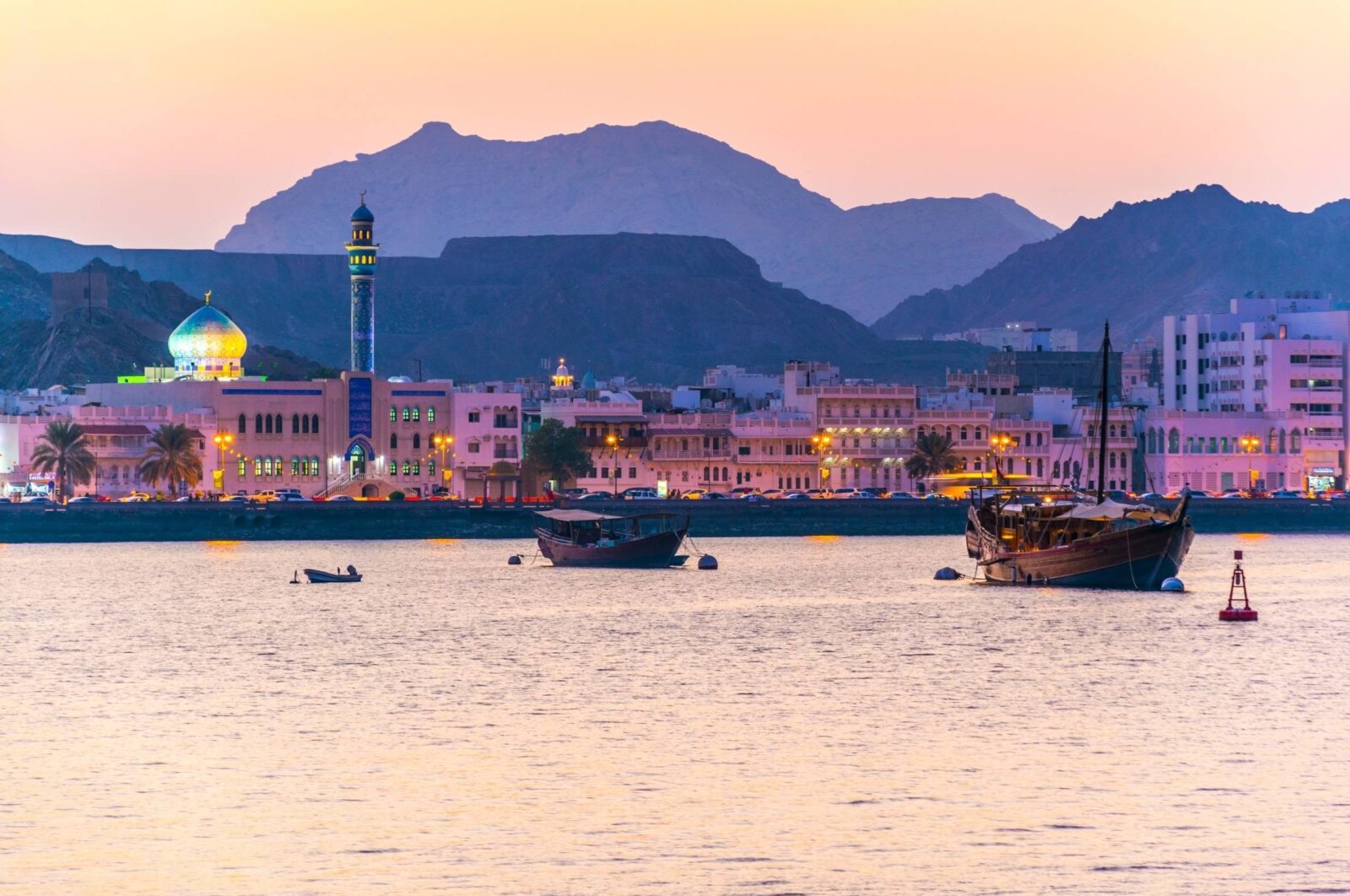 Sandy beach and turquoise sea in Muscat with palm trees and hotel buildings