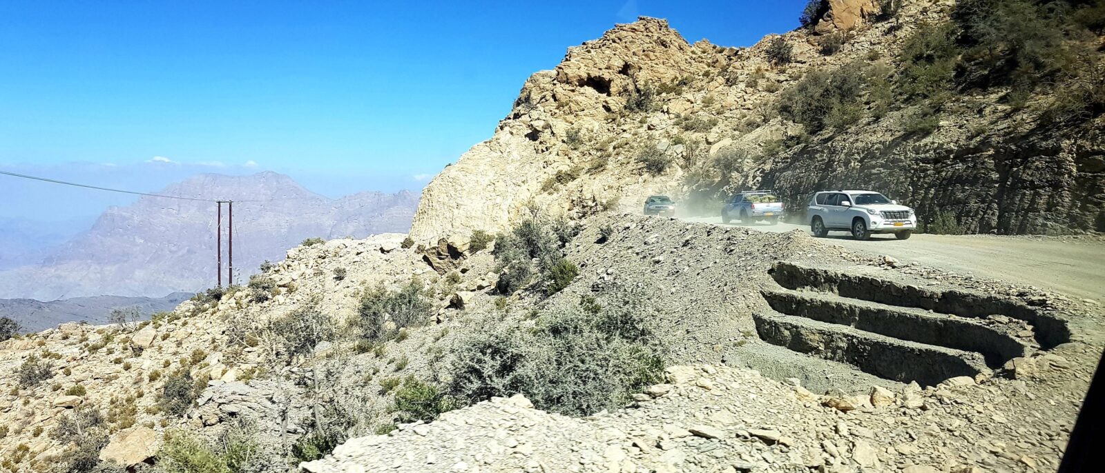 Historic Omani fort with round watchtower rising above palm trees and traditional houses