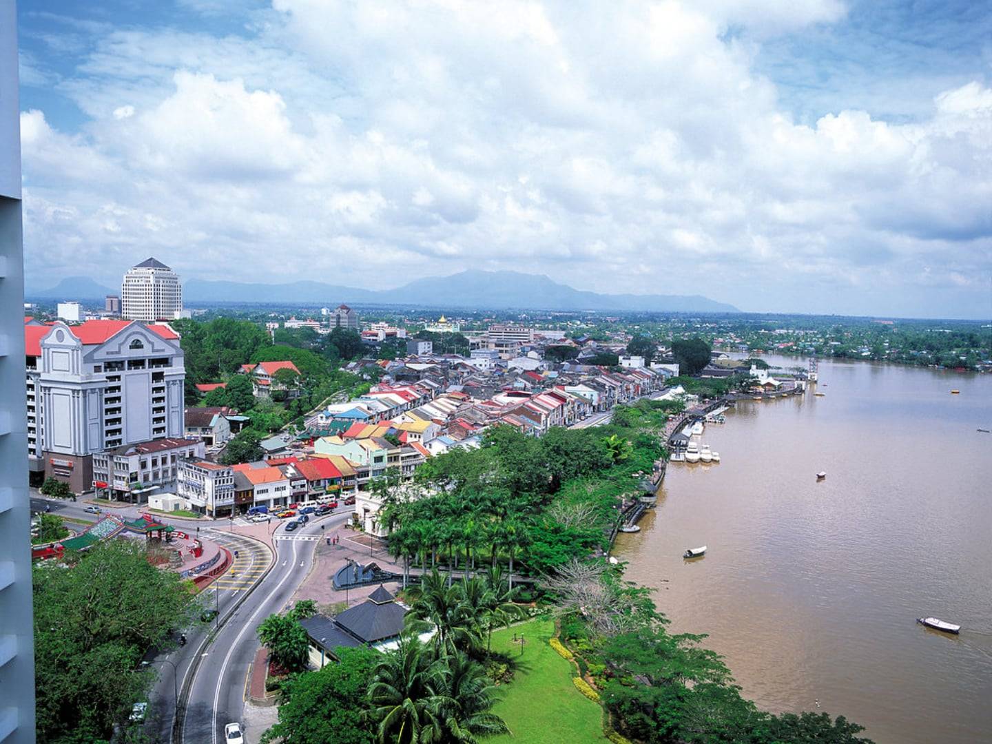 View over Kuching city and riverfront with traditional boats and modern buildings in the background