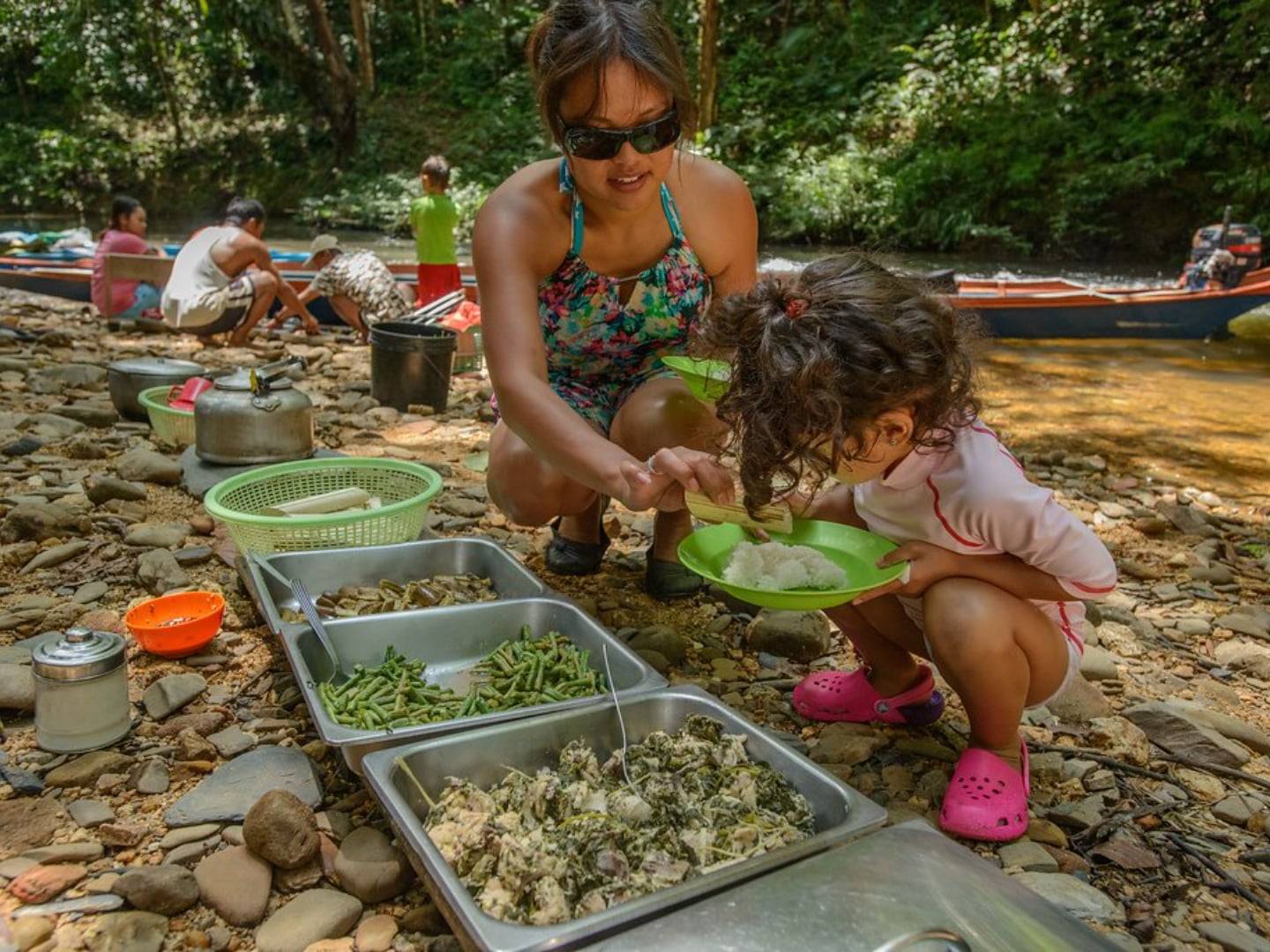 Longboat traveling downriver from the rainforest towards Batang Ai Lake under a cloudy sky