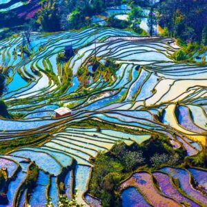 Mountain landscape near Lijiang in Yunnan with traditional village and terraced fields under a clear sky