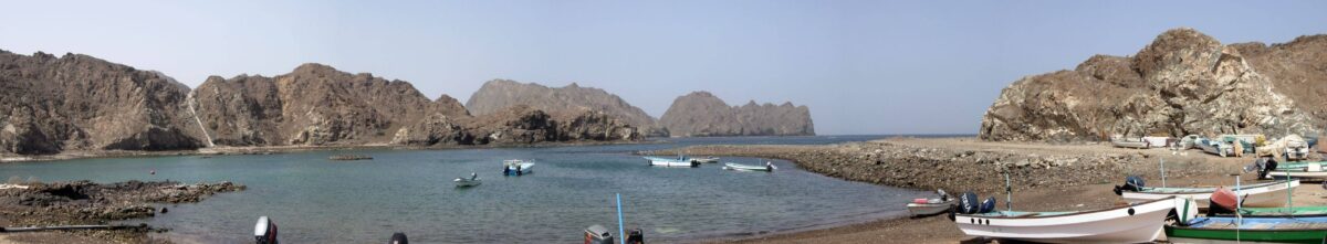 Quiet sandy beach near Muscat with turquoise sea and sun loungers in front of a beach resort