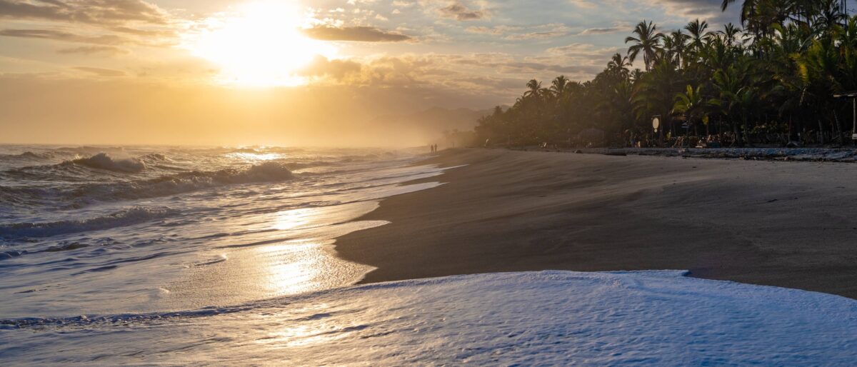 Relaxing tropical beach near Tayrona with hammocks strung between palm trees and gentle surf