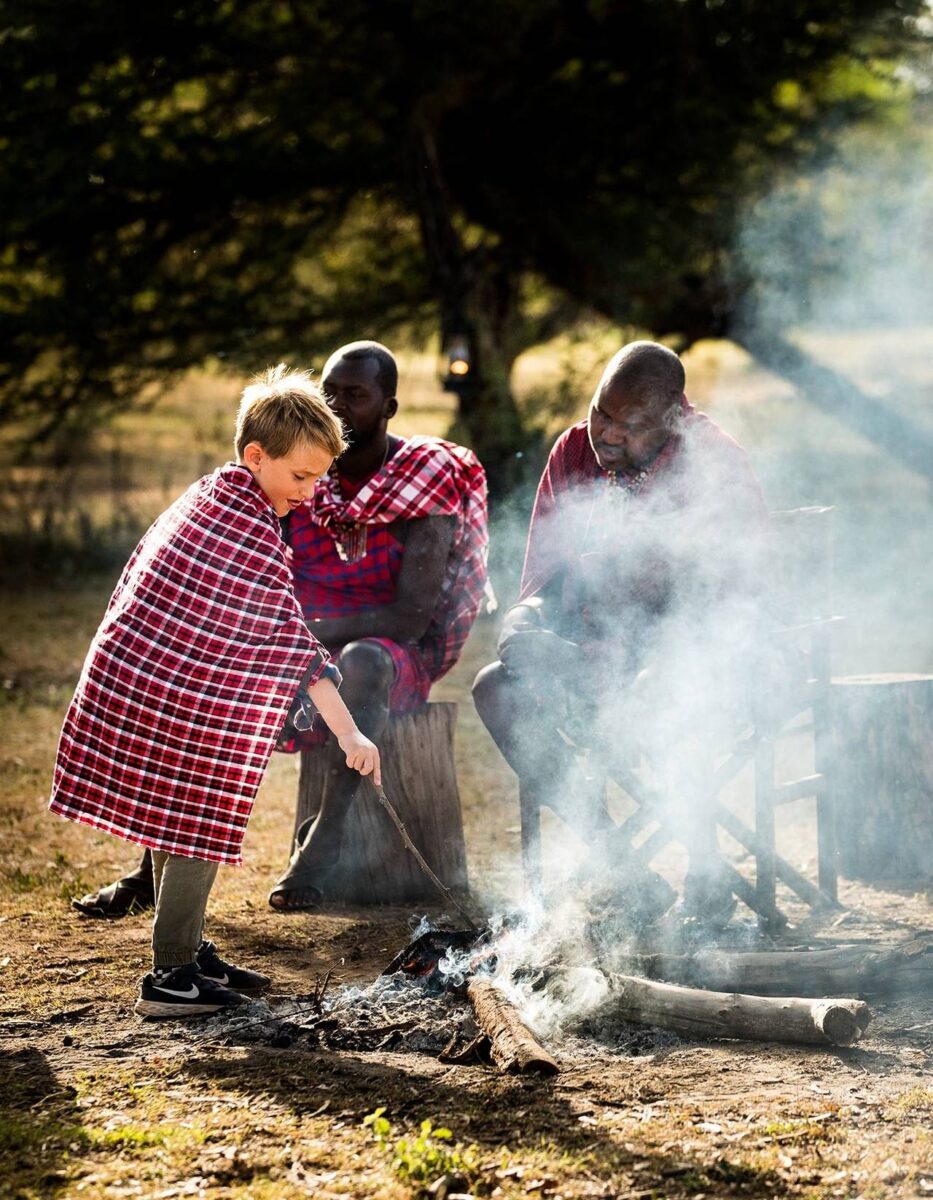 Road leading back to Nairobi with distant hills and a safari vehicle driving along