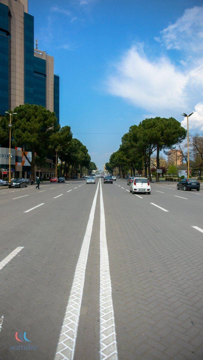 Road winding through green Albanian hills under a clear sky, symbolizing departure from Albania