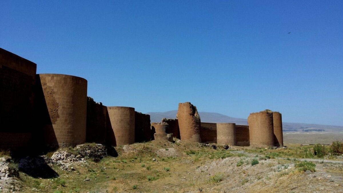 Ruins of a stone church in the ancient city of Ani on a grassy plateau above a river gorge