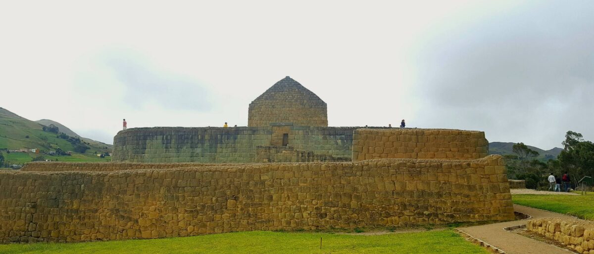 Ruins of the Inca site Ingapirca with green hills in the background under cloudy skies