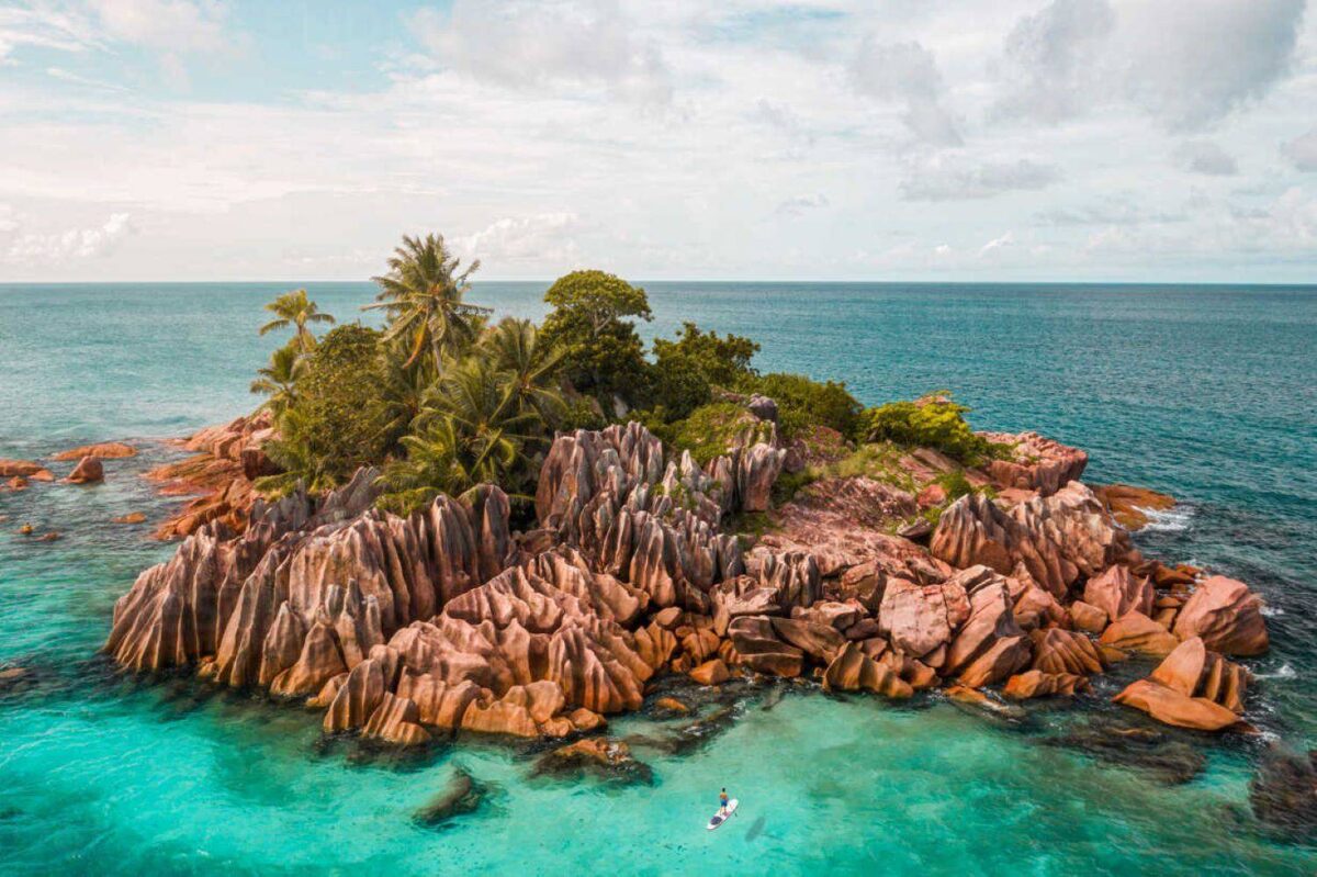 Small granite islet of St Pierre with palm trees rising from turquoise water, ideal for snorkeling