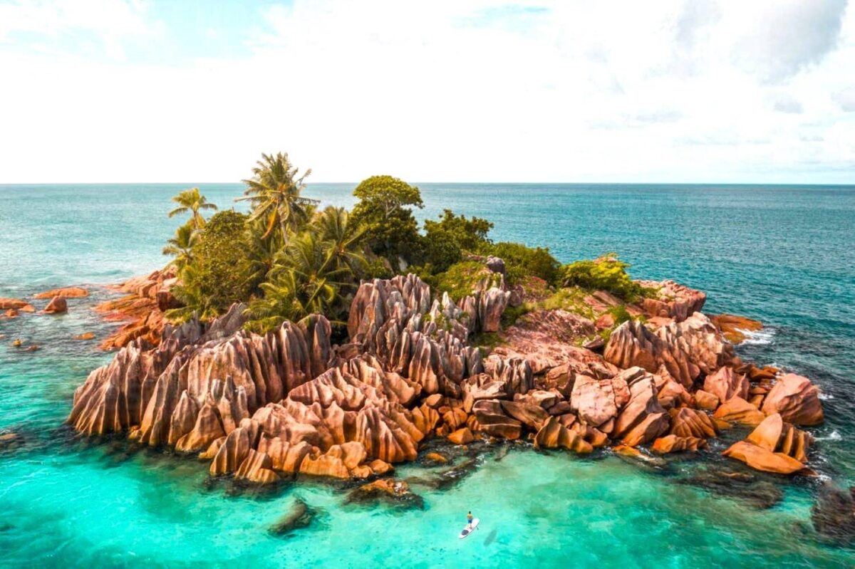 Small granite islet of St. Pierre with palm trees rising from turquoise waters near Praslin