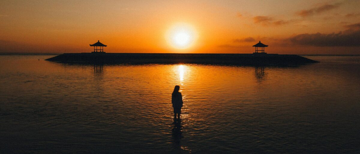 Speedboat leaving Gili Air for Bali with passengers looking back at the island’s palm-fringed shoreline
