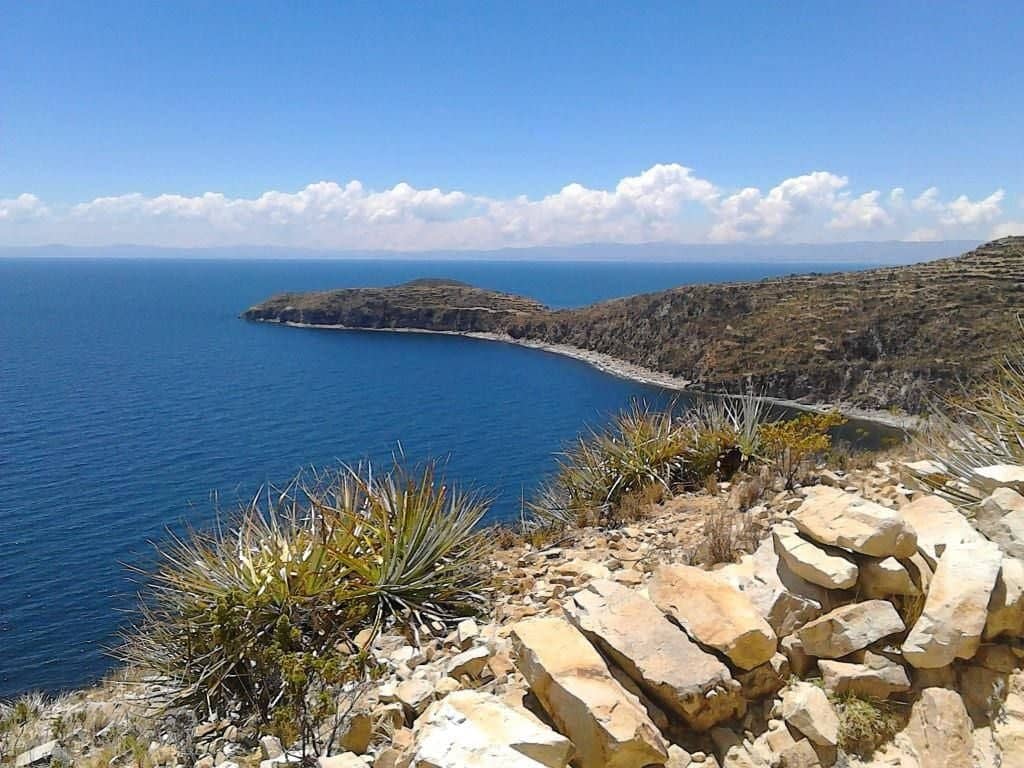 Stone paths and terraced hillsides on Isla del Sol overlooking the deep blue waters of Lake Titicaca and distant snow-capped peaks