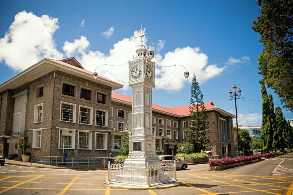 Street scene in Victoria, Seychelles with colorful market stalls, colonial buildings and lush hills behind
