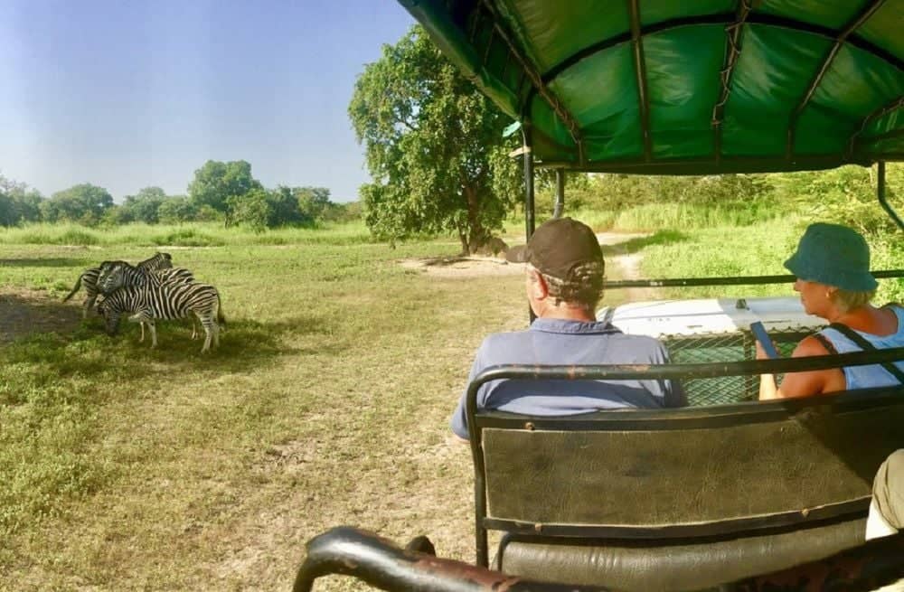 Sunset over the Saloum mangroves viewed from a shell mound with guests enjoying an aperitif by lantern light