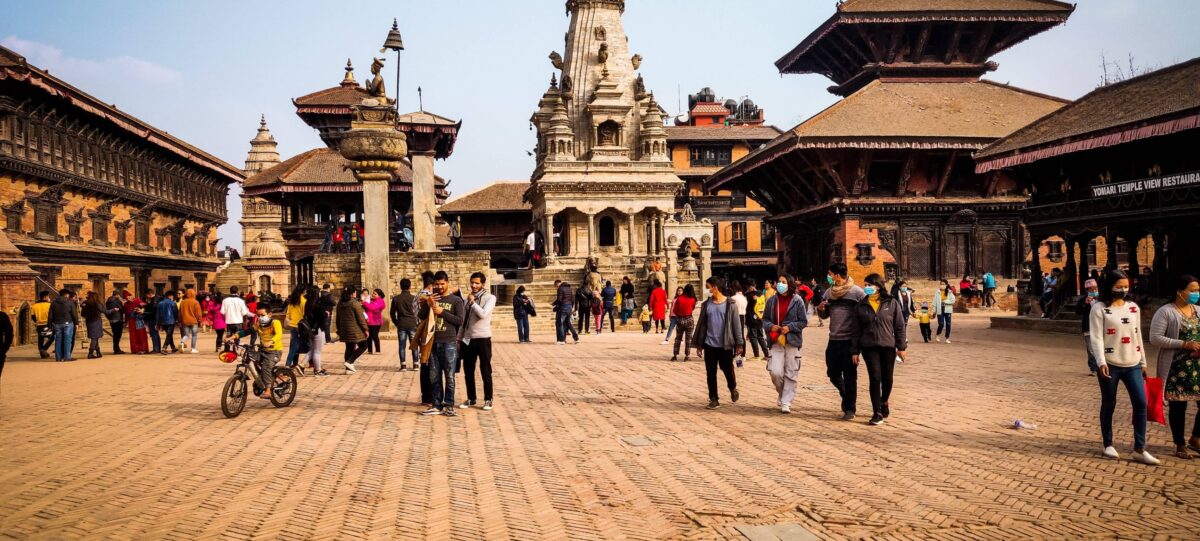 Traditional brick square in Bhaktapur with temples, pottery drying in the sun and locals walking through