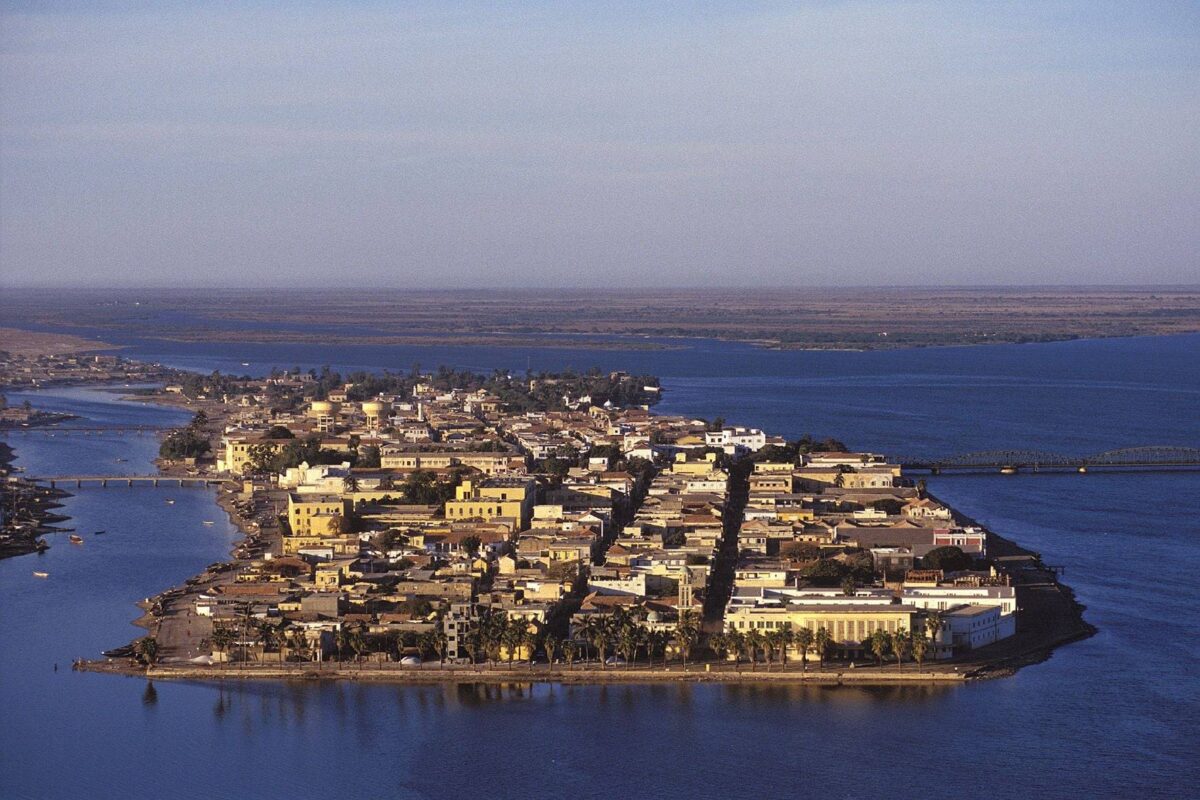 Traditional fishing pirogues lined up on a wide sandy beach of the Grande Côte near Saint-Louis, Senegal