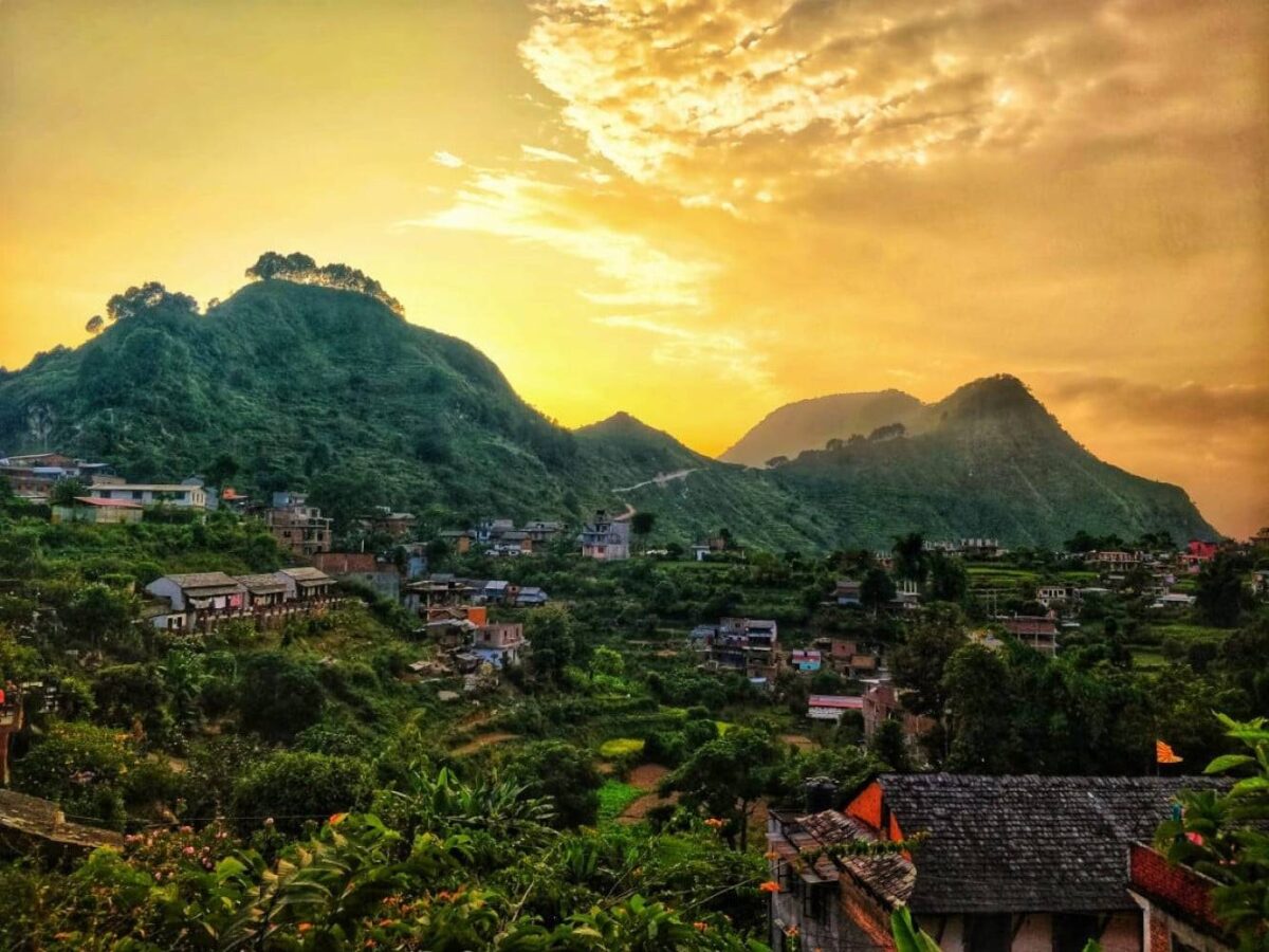 Traditional Newari houses lining a cobbled pedestrian street in Bandipur with mountain views in the distance