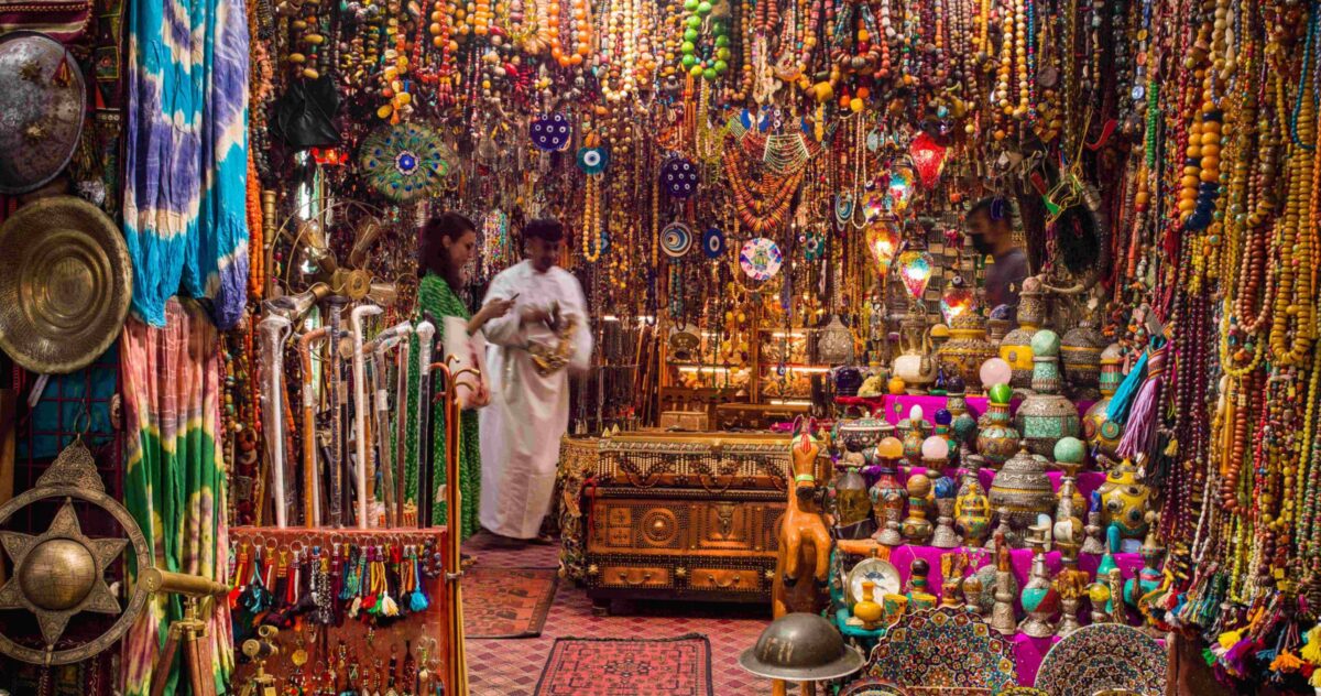 Traditional Omani dhows moored along the corniche in Sur with white houses and hills behind
