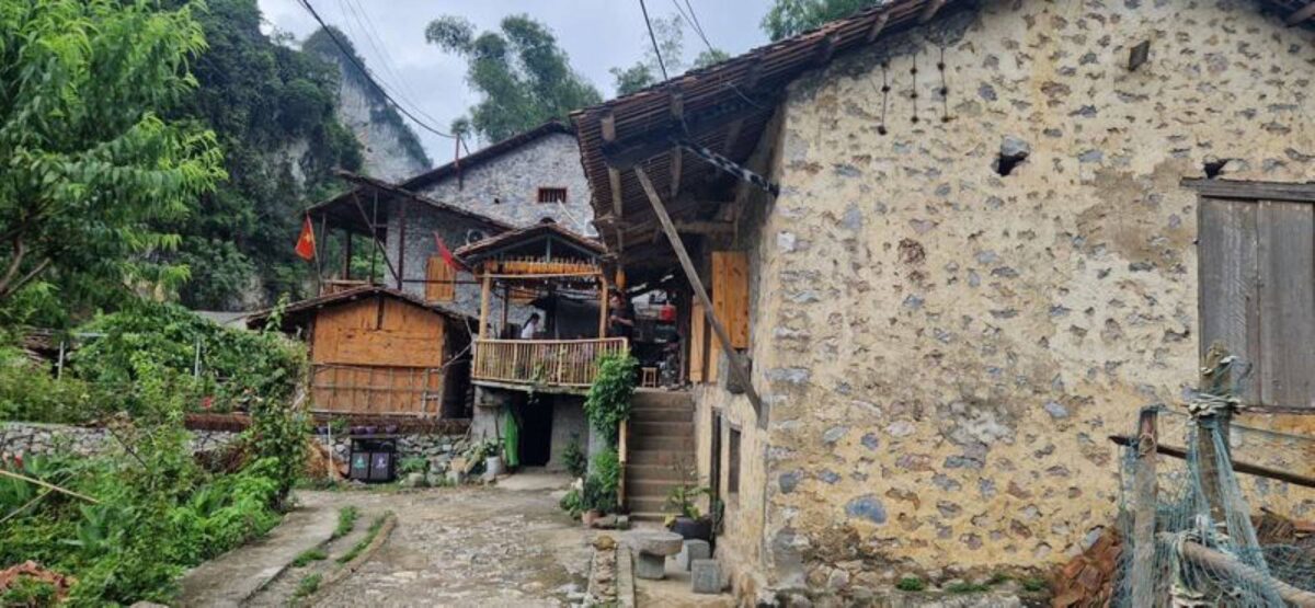Traditional stilt houses in a rural village near Cao Bang surrounded by karst hills, green fields and scattered trees