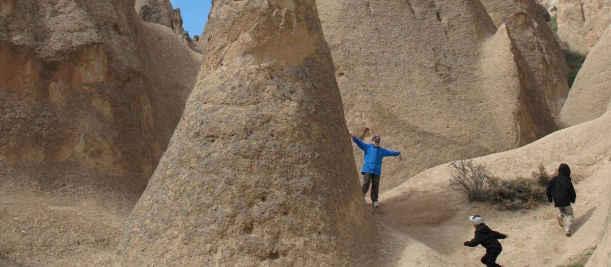 Traditional stone houses of Mustafapaşa village surrounded by rocky hills and fields in Cappadocia