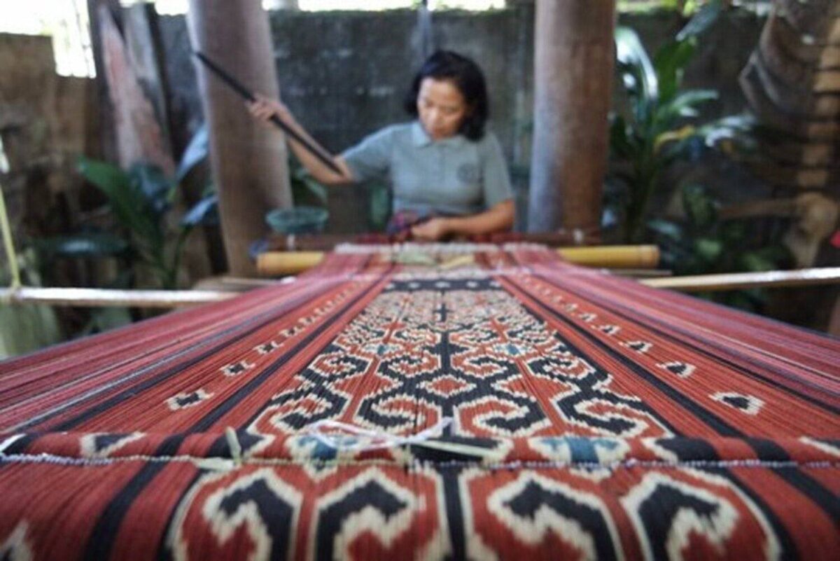 Traditional Toraja cliff graves at Lemo with carved balconies and wooden tau-tau ancestor figures overlooking rice fields