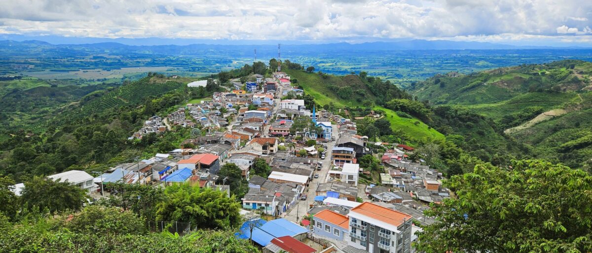 Traditional Willys Jeep parked on a mountain road overlooking green coffee plantations in Quindío