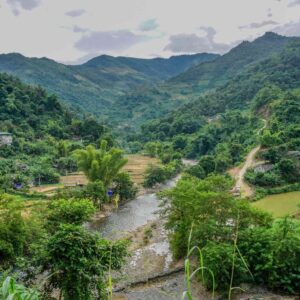 Traditional wooden boat cruising between limestone karst islands covered in lush green vegetation on the turquoise waters of Ha Long Bay in northern Vietnam at sunset