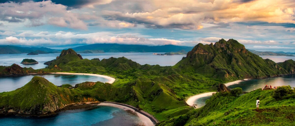 Traditional wooden boat cruising between small green islands near Labuan Bajo, Flores
