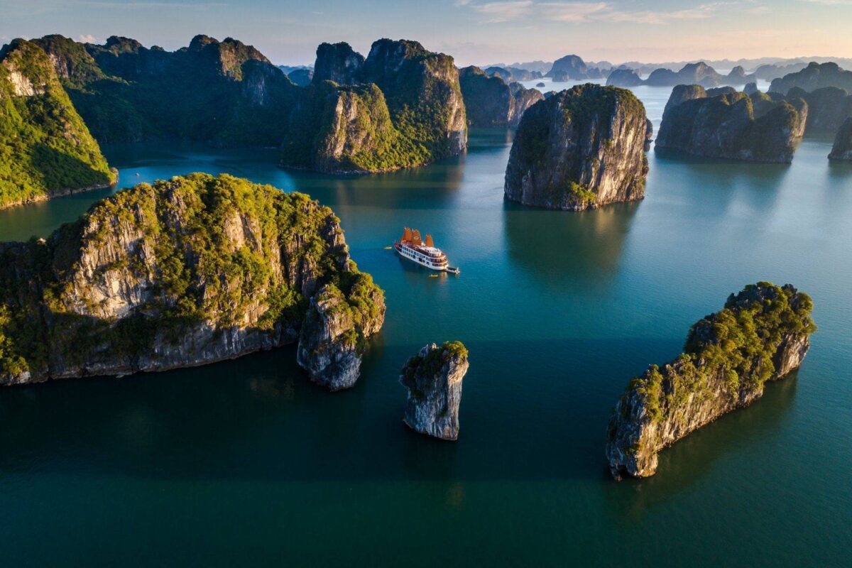 Traditional wooden junk boat cruising through the limestone islands of Halong Bay in Vietnam